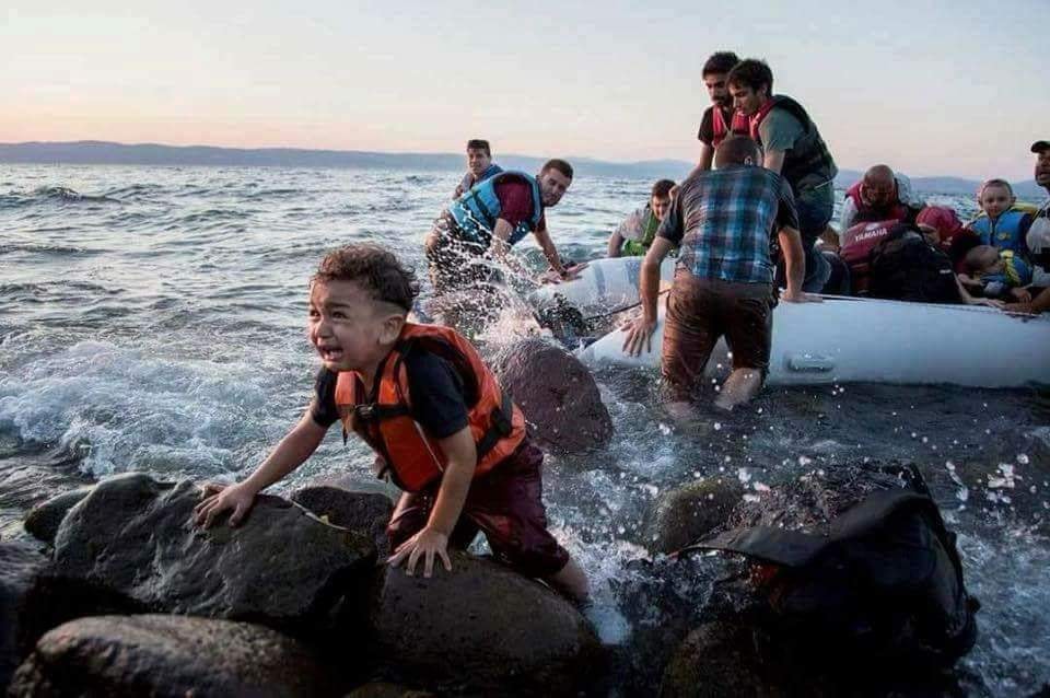 Famílias e crianças chegando à costa após travessia em barco inflável