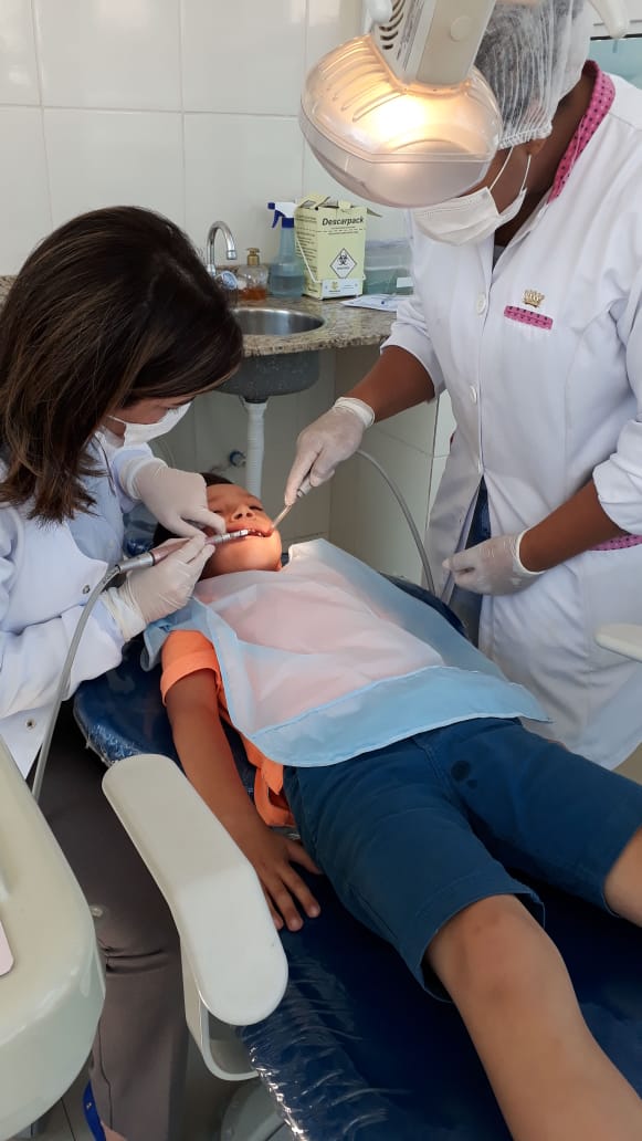 Criança recebendo atendimento odontológico em ação de assistência
